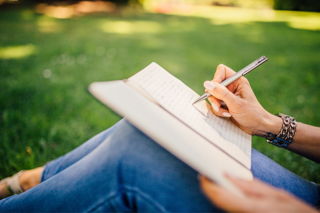 femme qui écrit dans un journal sur l'herbe