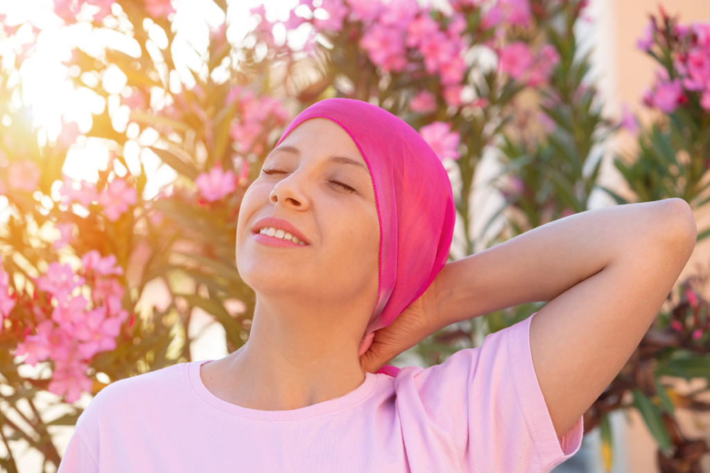 Femme avec un bandeau rose du cancer devant fleurs et arbres