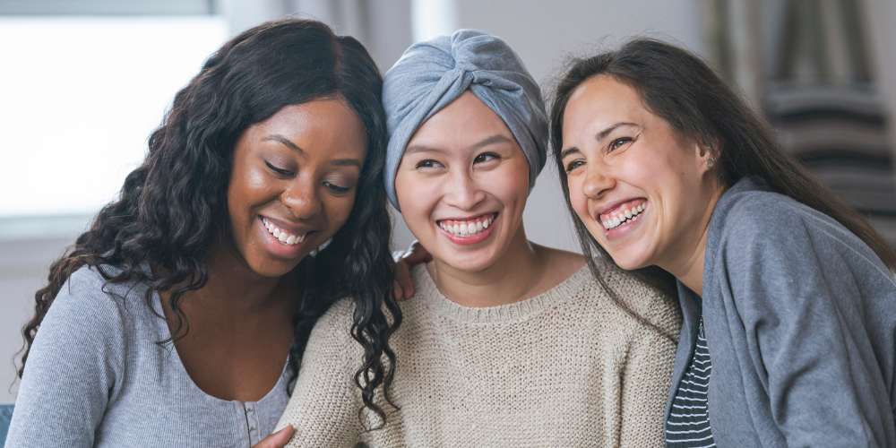 trio de femmes souriantes, une femme avec un bandeau, sensibilisation au cancer